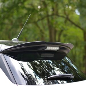 White SUV roof with a tall antenna and blurred green trees in the background.
